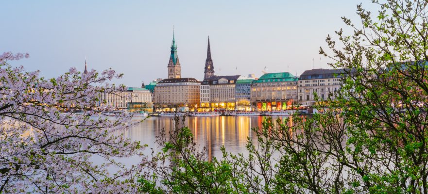 Beautiful panoramic view of Alster river and Hamburg town hall - Rathaus at spring earning evening during golden hour. Panoramic Banner shot.